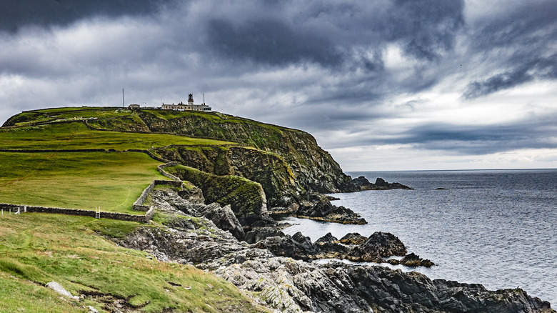 Faro de Sumburgh Head en el sur de las Shetland continentales, situado sobre un acantilado con nubes de tormenta detrás