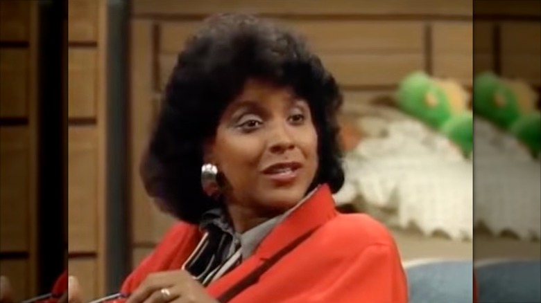 Phylicia Rashad con aros plateados y un blazer naranja
