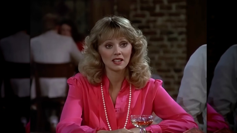 Shelley Long con una blusa rosa intenso y un collar largo de perlas.