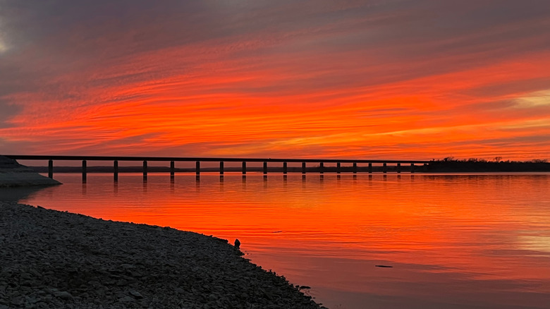 Puesta de sol naranja sobre el lago Whitney con un puente que cruza el horizonte.