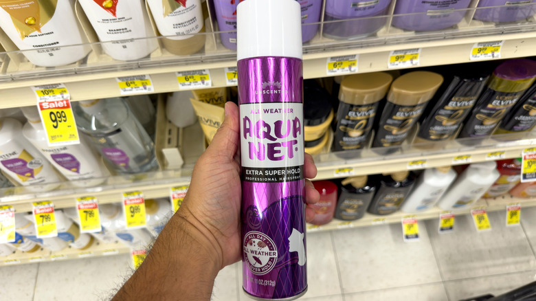 Una persona sosteniendo una lata de laca para el cabello Aqua Net de los años 80.