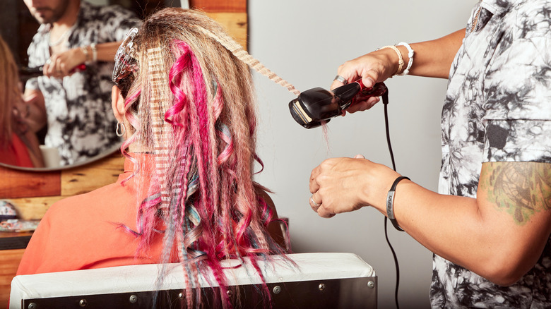 Un estilista que riza el cabello colorido.