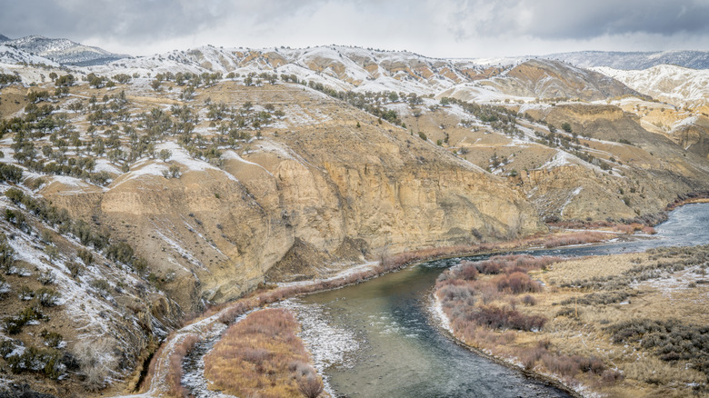 Alto río Colorado bordeado por montañas cubiertas de nieve y artemisa en Dotsero durante el invierno.