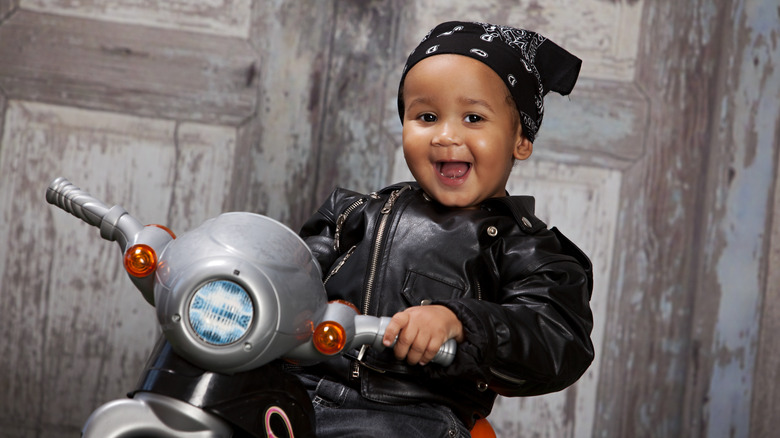 Bebé con chaqueta de cuero en una motocicleta de juguete