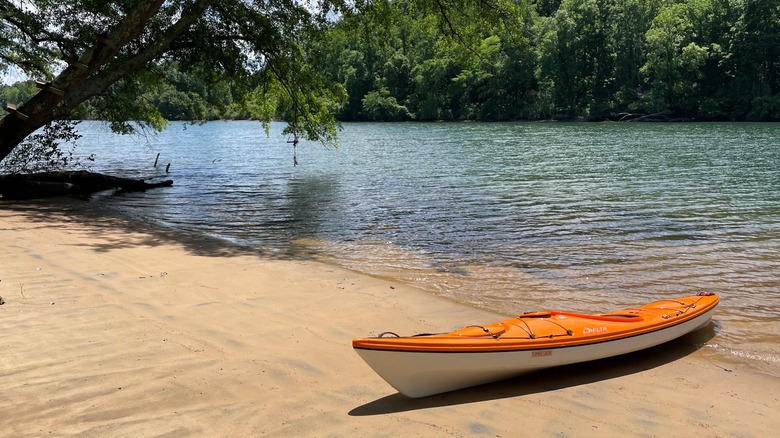 Kayak naranja y blanco en la orilla arenosa de Mountain Island Lake, Carolina del Norte