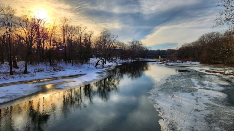 Una fiesta en el río congelada con nieve en las orillas, invierno en la Reserva Natural Marott Woods al atardecer