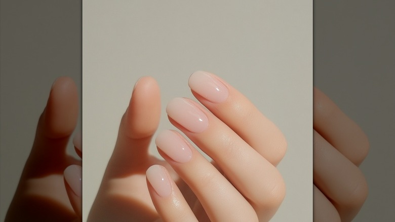La mano de una mujer con una manicura con leche de coco.