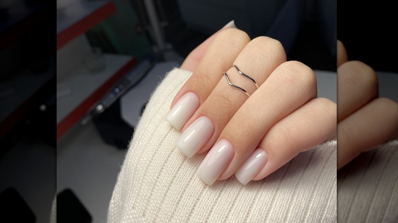 La mano de una mujer con una manicura con leche de coco.