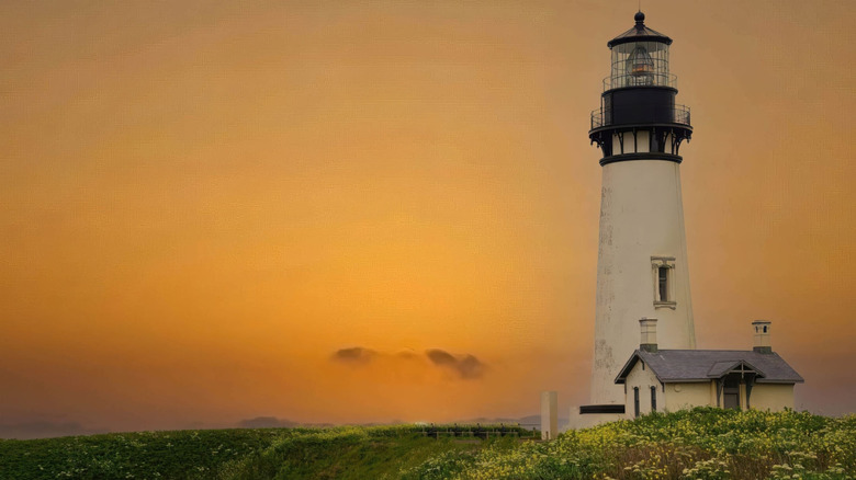 El faro de Yaquina Head en Newport, Oregón, con un cielo nublado de color naranja al fondo