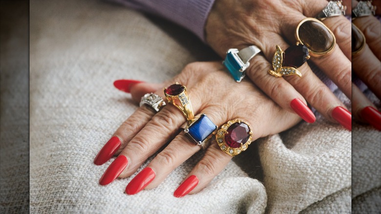 Largas uñas rojas con anillos gruesos.