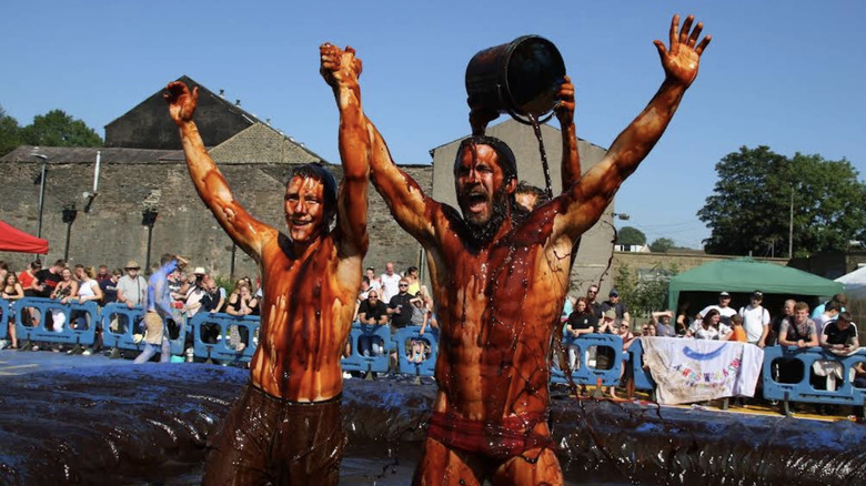 Un hombre arroja un cubo de salsa sobre un competidor en el campeonato World Gravy Wrestling.