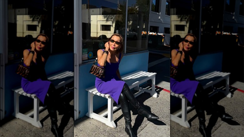 Gym Tan con un vestido ajustado morado y botas hasta los muslos