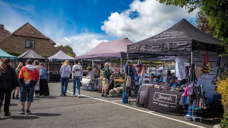 Gente explorando puestos de comida y artesanía en un día soleado en el mercado artesanal de Billingshurst