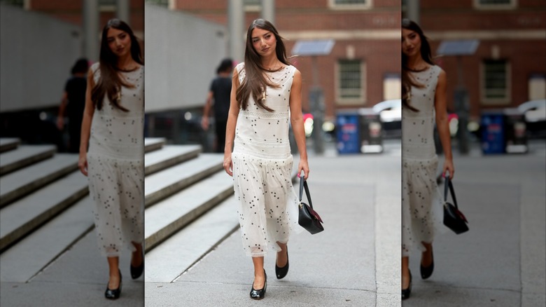 Una mujer que llevaba un vestido blanco con cintura caída.
