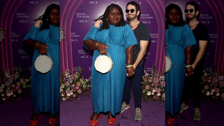 Gabourey Sidibe con un vestido azul y zapatos rojos posa junto a su marido Brandon Frankel