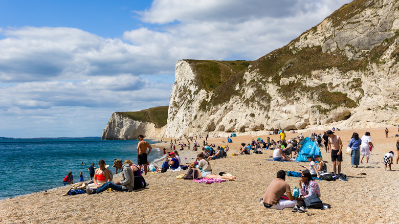 La gente toma el sol en las arenas de la playa de Durdle Door en verano