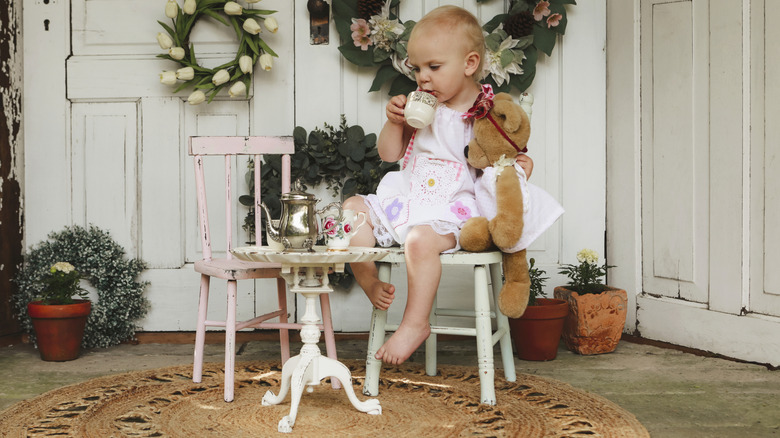Una niña pequeña tomando un té con su osito de peluche