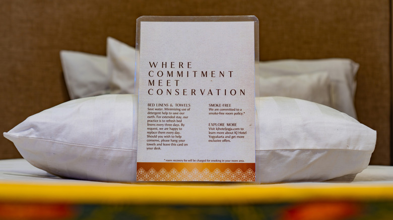 Un compromiso de conservación y un aviso en una habitación de hotel apoyada sobre una almohada