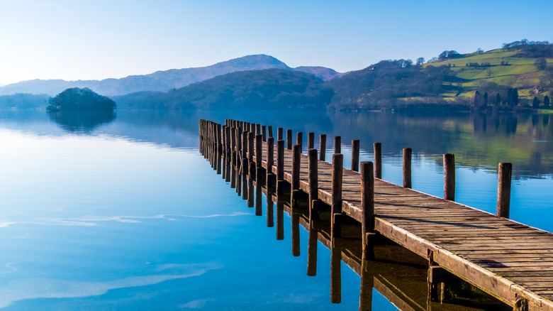 Muelle de madera que se extiende hacia Coniston Water, Lake District National Park, Inglaterra, con aguas tranquilas y un telón de fondo montañoso