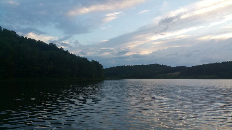 El lago Beechwood de Pensylvania, con agua rodeada de colinas arboladas bajo un cielo azul nublado