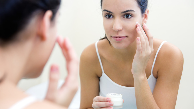 Mujer aplicándose crema en la cara