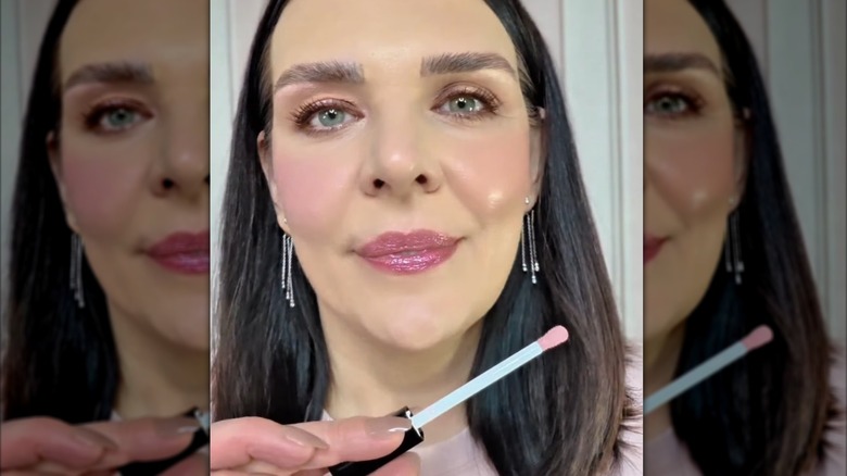 Mujer aplicando brillo de labios rosa