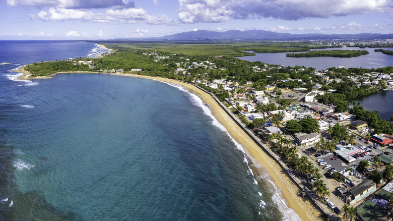 La costa arenosa de Loíza, Puerto Rico, con un exuberante follaje verde y edificios costeros
