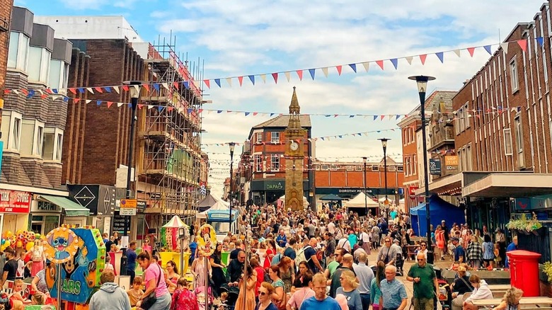 Multitud colorida y edificios históricos junto con la Torre del Reloj de Ormskirk en el fondo del Festival de pan de jengibre de Ormskirk al aire libre