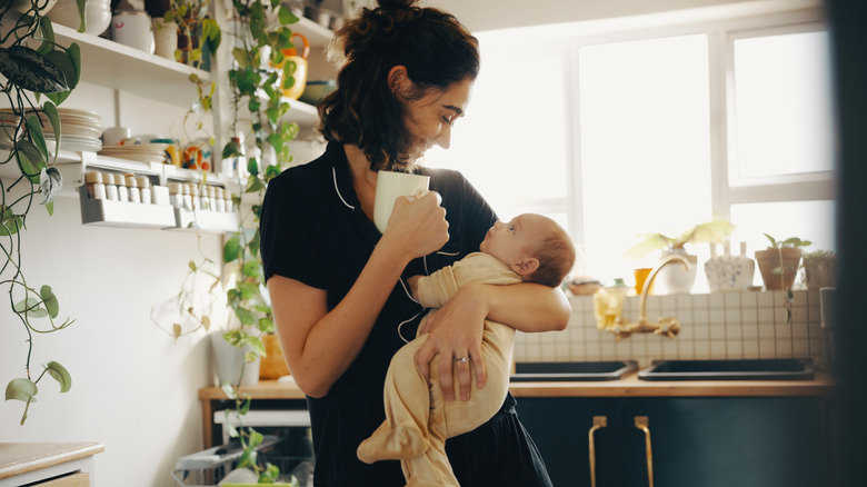 Una madre sosteniendo a su bebé en la cocina.