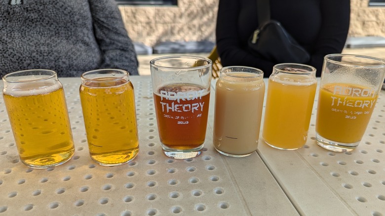 Una selección de cerveza artesanal expuesta en una mesa con un par de vasos de marca de Adroit Theory Brewing Company en Purcellville, Virginia.