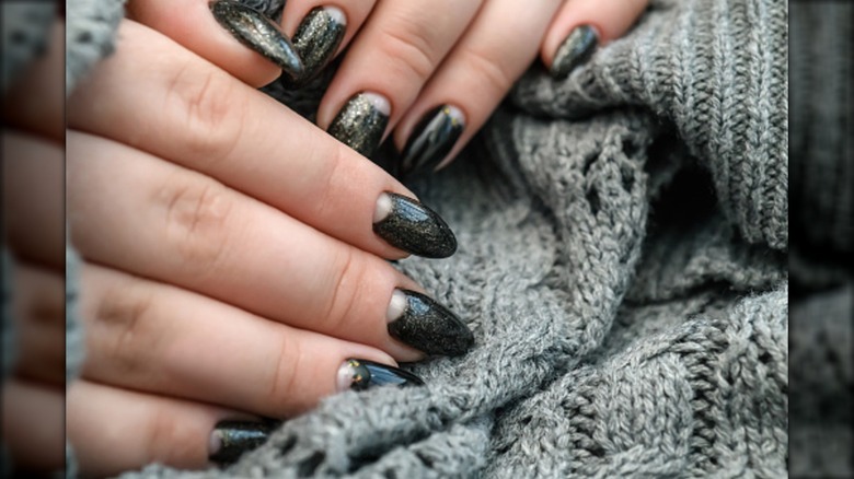 Una manicura en forma de media luna con esmalte de uñas con brillo oscuro.