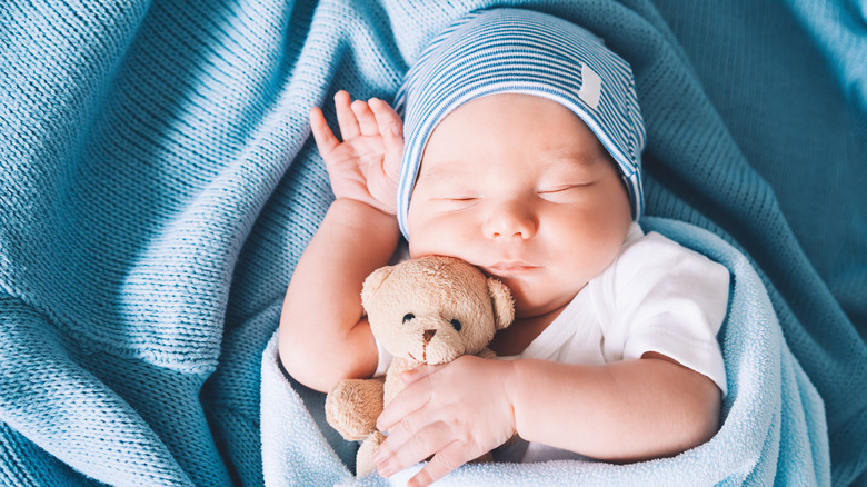 Un bebé durmiendo tranquilamente mientras sostiene un peluche