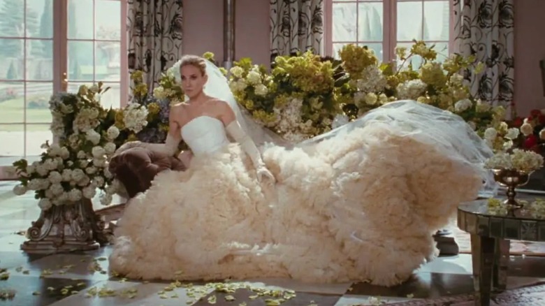 Sarah Jessica Parker como Carrie Bradshaw sentada con un llamativo vestido de novia y guantes.