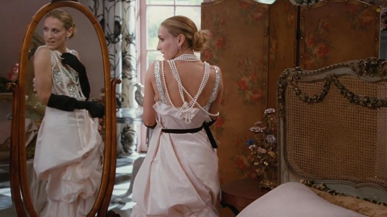 Sarah Jessica Parker como Carrie Bradshaw con un vestido de novia drapeado con guantes negros y collares de perlas.