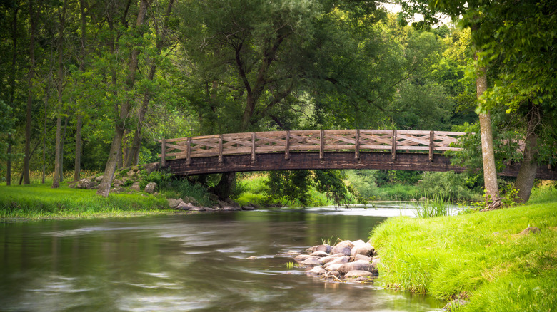 El agua tranquila fluye debajo de un puente de madera en el parque del condado de Covered Bridge en Wisconsin.