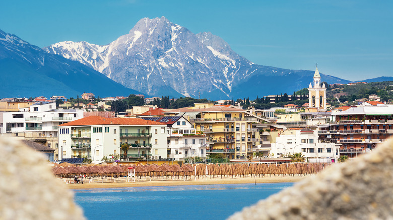 El paseo marítimo de Pescara con palapas, edificios y montañas escarpadas al fondo