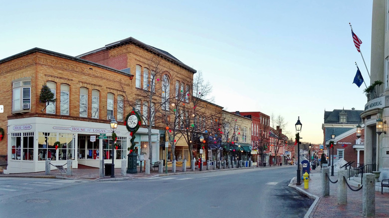 Una calle en Bath, Maine, rodeada de edificios históricos y un cielo vacío, todo adornado para la temporada navideña.
