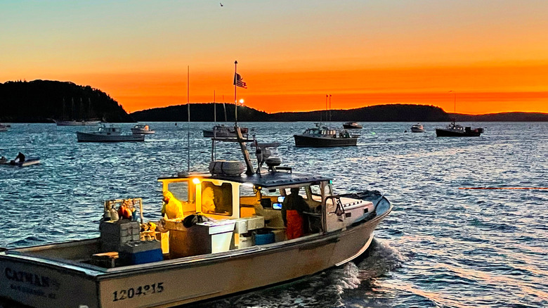 Un barco langostero se dirige al mar frente a la costa de Maine al amanecer.
