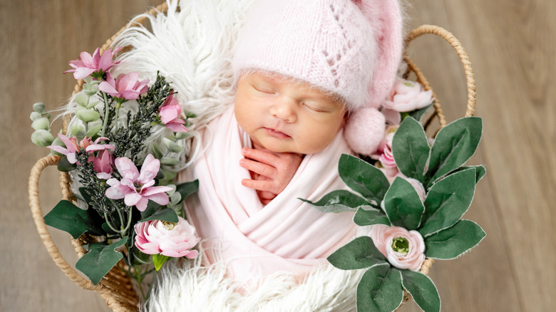 Una niña durmiendo en una cesta de flores.