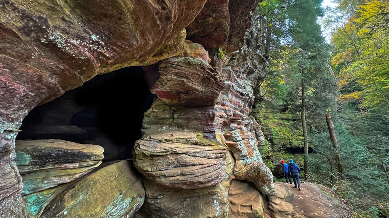 Excursionistas junto a formaciones rocosas curvas y árboles altos en el Parque Estatal Hocking Hills, Ohio