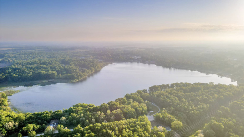 Una vista aérea del lago Stone rodeado de árboles mientras se pone el sol en el condado de Cass, Michigan